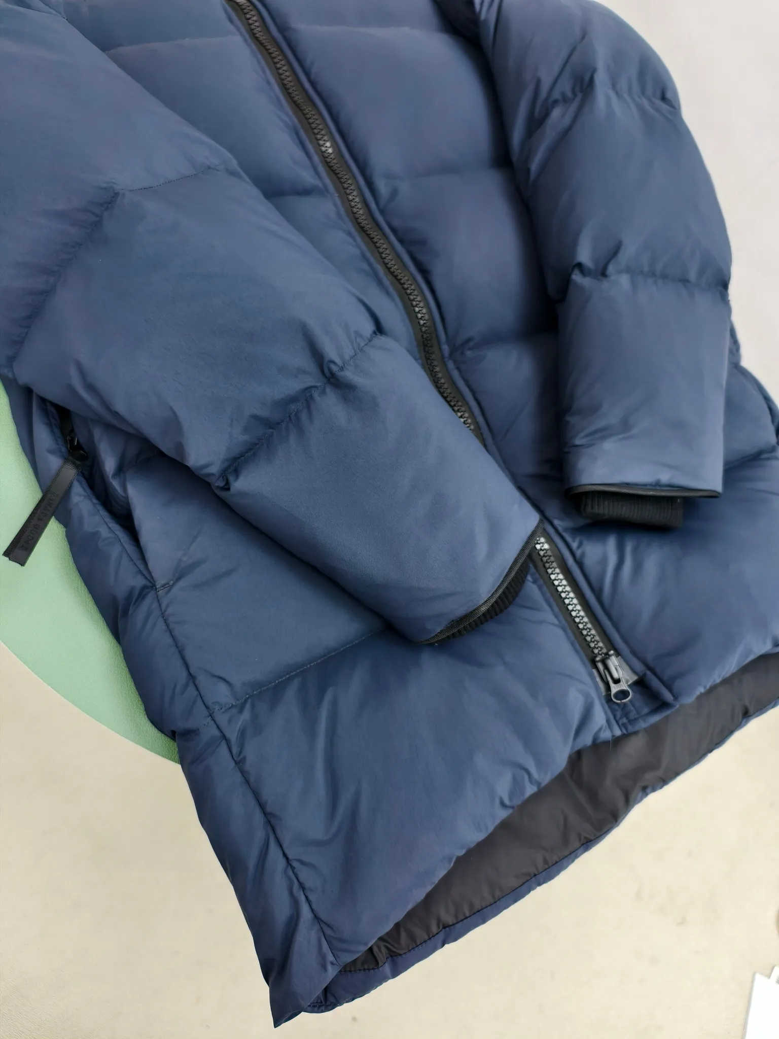 P940 Canada Goose Lawrence Down Jacket The Lawrence Down Jacket provides essential protection for everyday adventures and is made from sustainable Enduraluxe fabric with a durable soft touch. It features a quilted body, an adjustable down hood and a longer hem. Adjustable, down-filled, communicated hood. Two-way center front zipper increases range of motion and ventilation. The chin-protecting suede knit stand-up collar is soft and extra-comfortable. Inset rib-knit cuffs for added comfort and locked in heat. CORDURAD piping at the cuffs hem and reflective double-stripe grip tape at the back. Internal shoulder strap Color: black with red label black with black label azure blue Size: XS-2XL